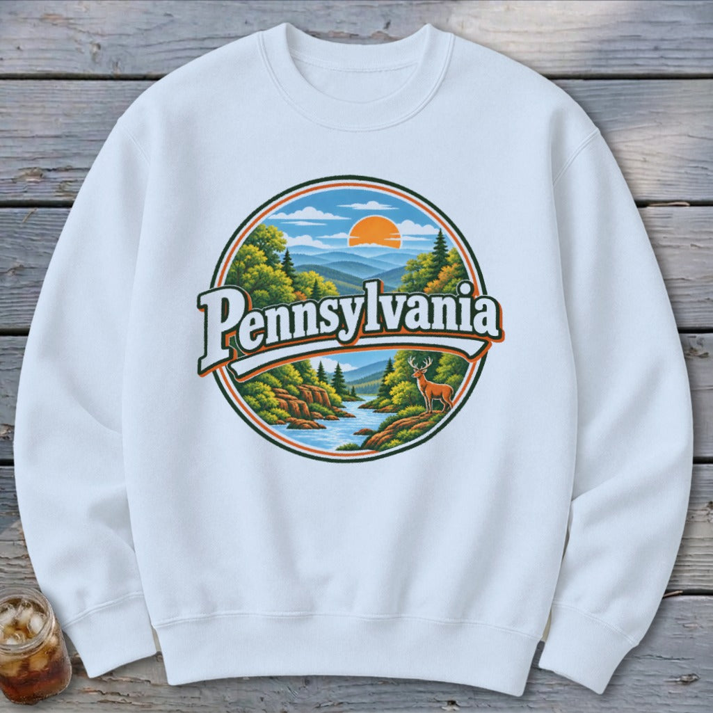 White sweatshirt with a circular Pennsylvania nature graphic featuring mountains, river, trees, deer, and sun.