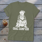 Olive green t-shirt with white graphic of a seated boy with a bucket and "COAL CAMP KID" text.
