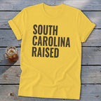Yellow t-shirt with "SOUTH CAROLINA RAISED" text in dark gray.