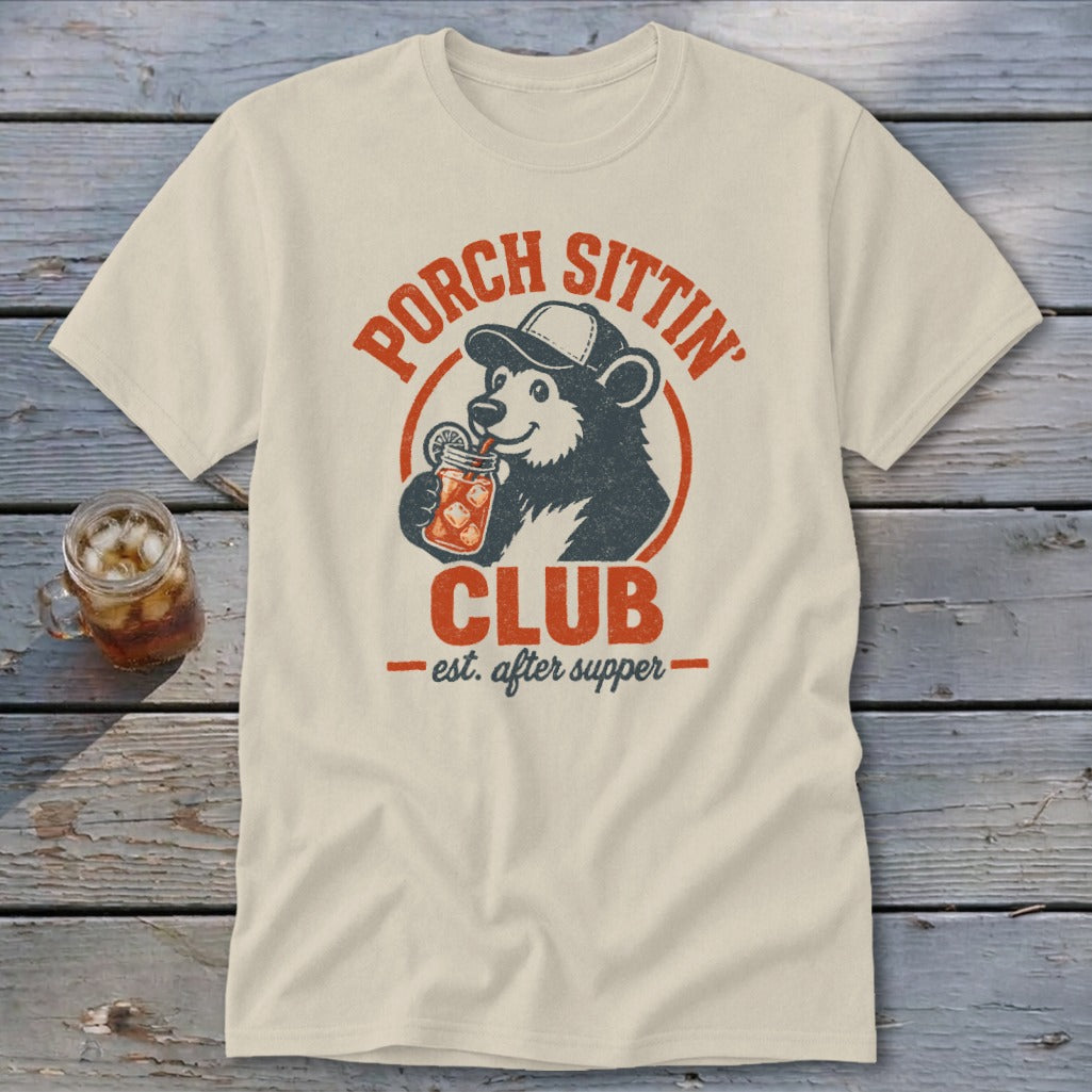 Cream t-shirt with distressed graphic of a bear wearing a cap, drinking from a jar. Text reads "Porch Sittin' Club".
