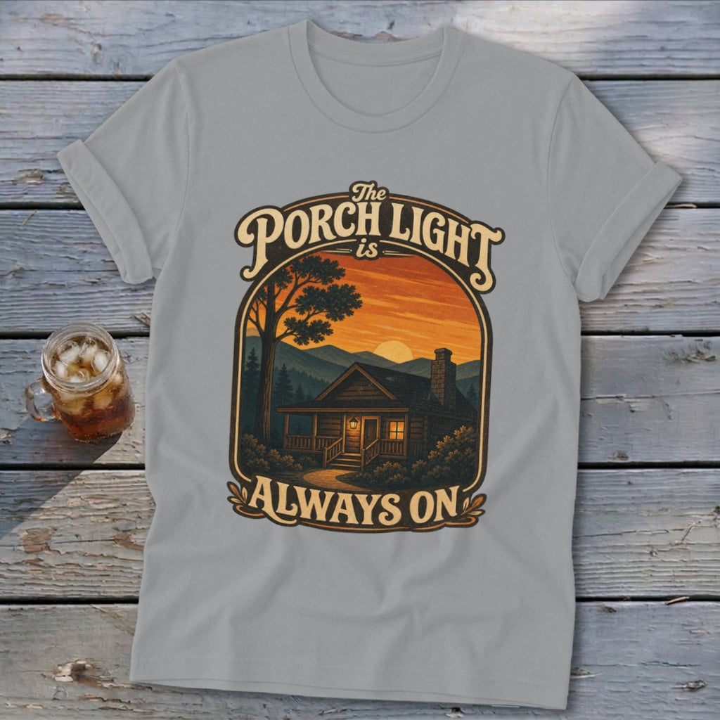 Light grey t-shirt with graphic "The Porch Light is Always On" over a cabin at sunset.