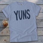 Light blue t-shirt with "YUNS" text in dark blue letters.