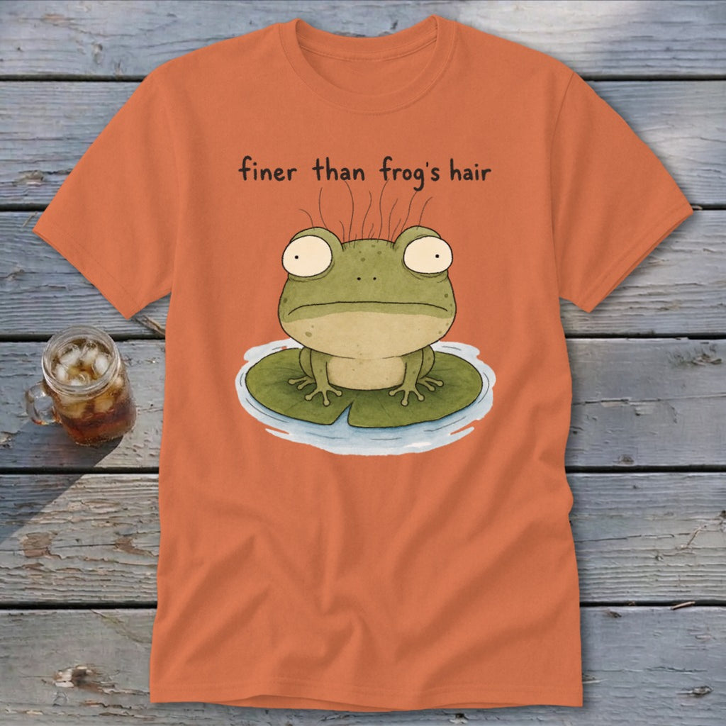An orange t-shirt features a cartoon illustration of a frog on a lily pad with text reading finer than frog's hair.