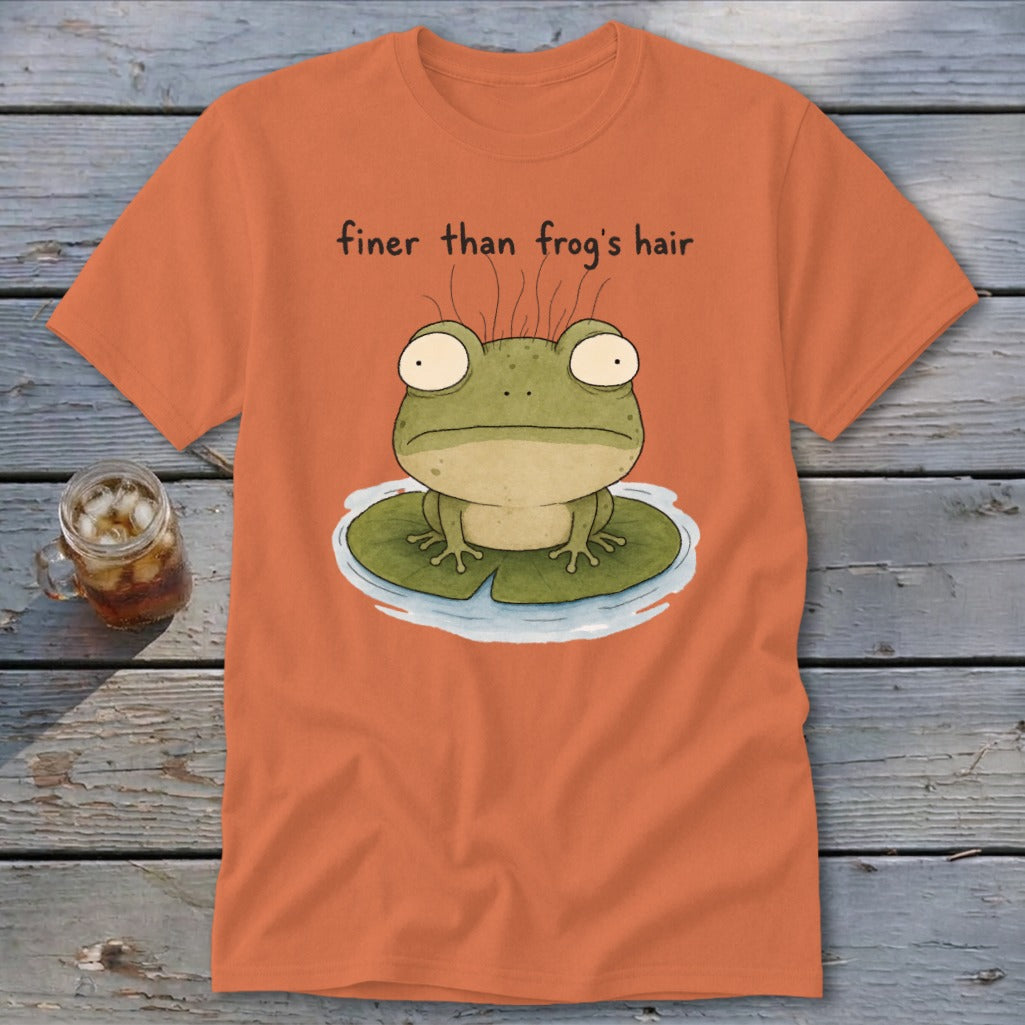 An orange t-shirt features a cartoon illustration of a frog on a lily pad with text reading finer than frog's hair.