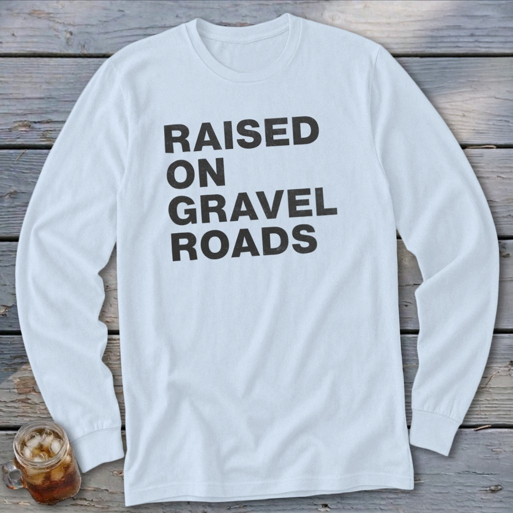 White long-sleeved shirt with "RAISED ON GRAVEL ROADS" printed in black text.
