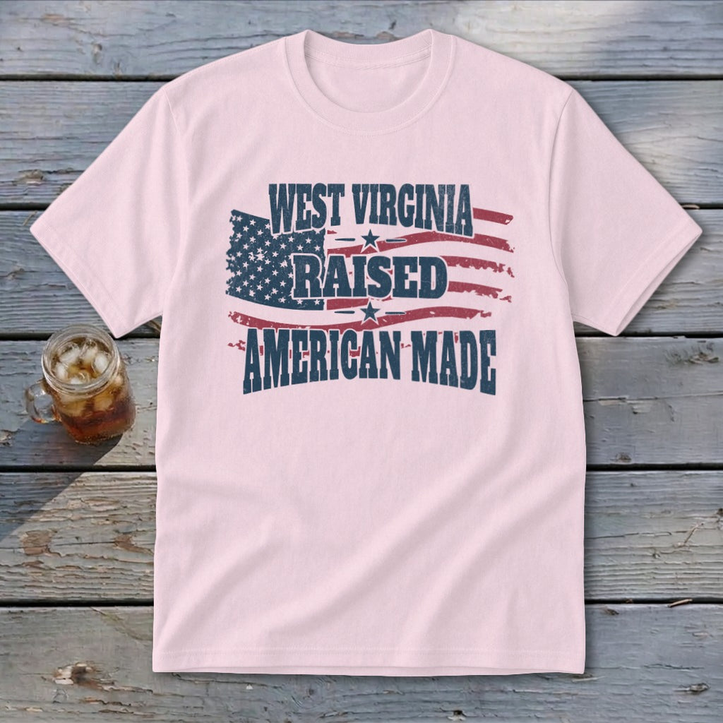 Light pink t-shirt featuring a distressed American flag graphic and text reading West Virginia Raised American Made.