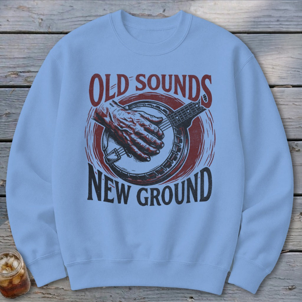 Light blue crewneck sweatshirt featuring a graphic of a hand playing a banjo and text reading Old Sounds New Ground.
