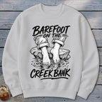 Light gray sweatshirt with "Barefoot on the Creek Bank" graphic and bare feet.