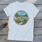 White t-shirt with a circular graphic of a mountain landscape with "North Carolina" text.