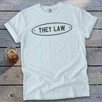 White t-shirt with oval graphic and "THEY LAW" text.