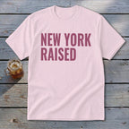 Pink t-shirt with "NEW YORK RAISED" text in dark pink lettering.
