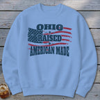 Light blue crewneck sweatshirt featuring a distressed graphic of the American flag and text that reads Ohio Raised American Made.