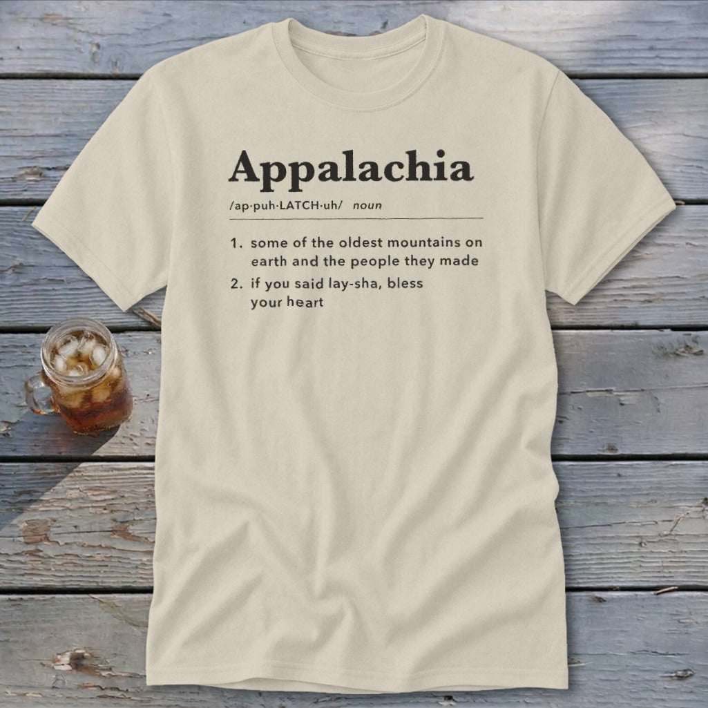 Cream-colored t-shirt with black text defining Appalachia displayed on a rustic wooden background.