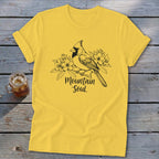 Yellow t-shirt with black ink drawing of cardinal on a branch with flowers and text "Mountain Soul".