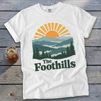 White t-shirt with sunrise over mountains and "The Foothills" text.
