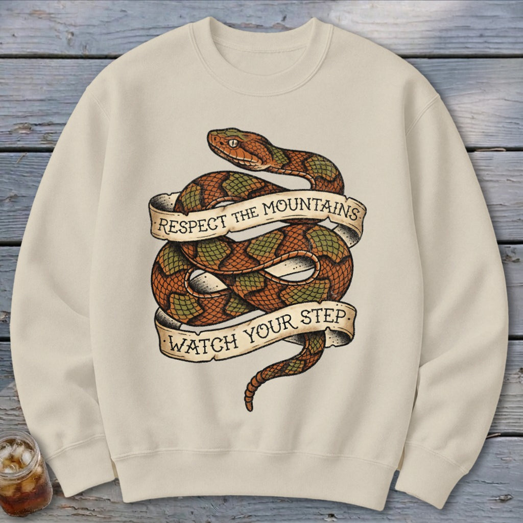Cream sweatshirt with a coiled snake design and text "Respect the Mountains Watch Your Step".