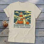 Beige t-shirt featuring a graphic of a stack of pumpkins and mountains with text that reads harvest days in the highlands.