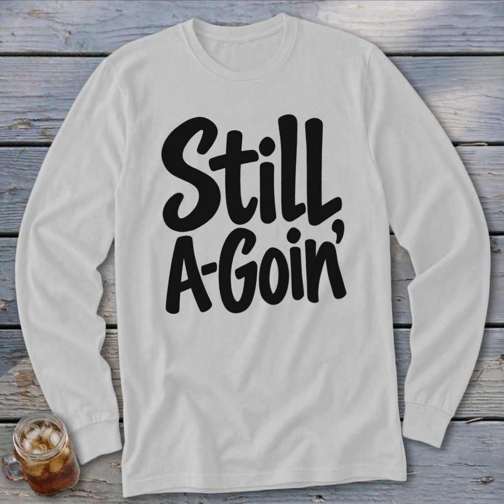 Light gray long-sleeved crewneck shirt with black text reading "Still A-Goin'".