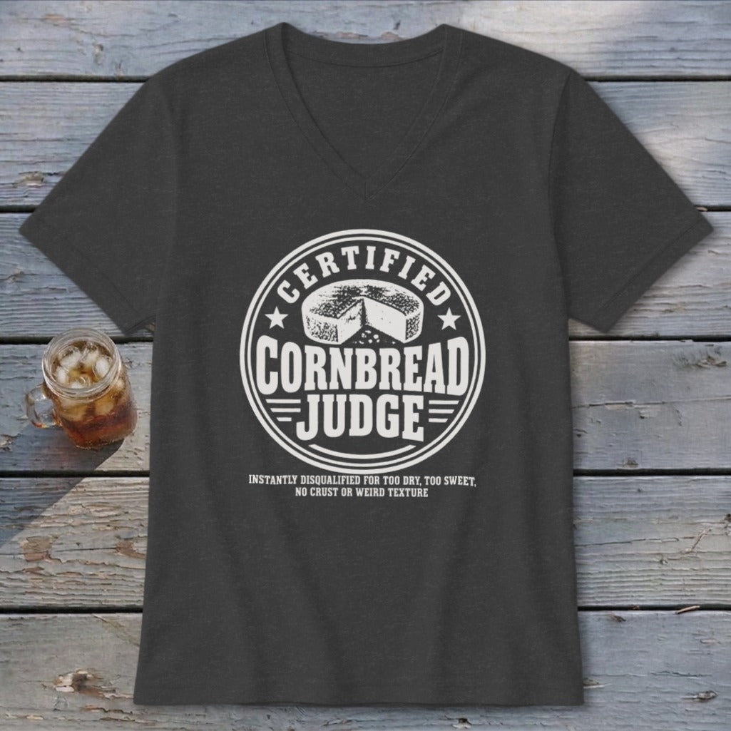A dark gray v-neck t-shirt with white graphic text reading Certified Cornbread Judge and a round cheese illustration.