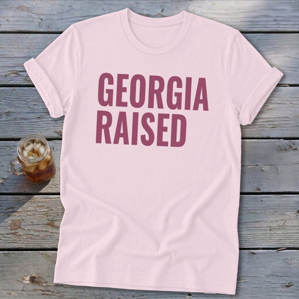 Light pink t-shirt with "GEORGIA RAISED" in dark pink text.