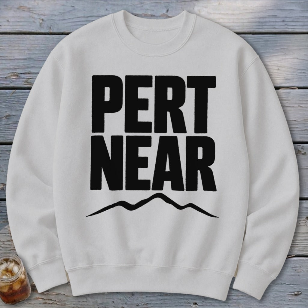 Off-white crewneck sweatshirt featuring bold black text reading PERT NEAR above a simple mountain outline.