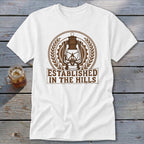 White t-shirt with a brown lantern emblem and "ESTABLISHED IN THE HILLS" text.