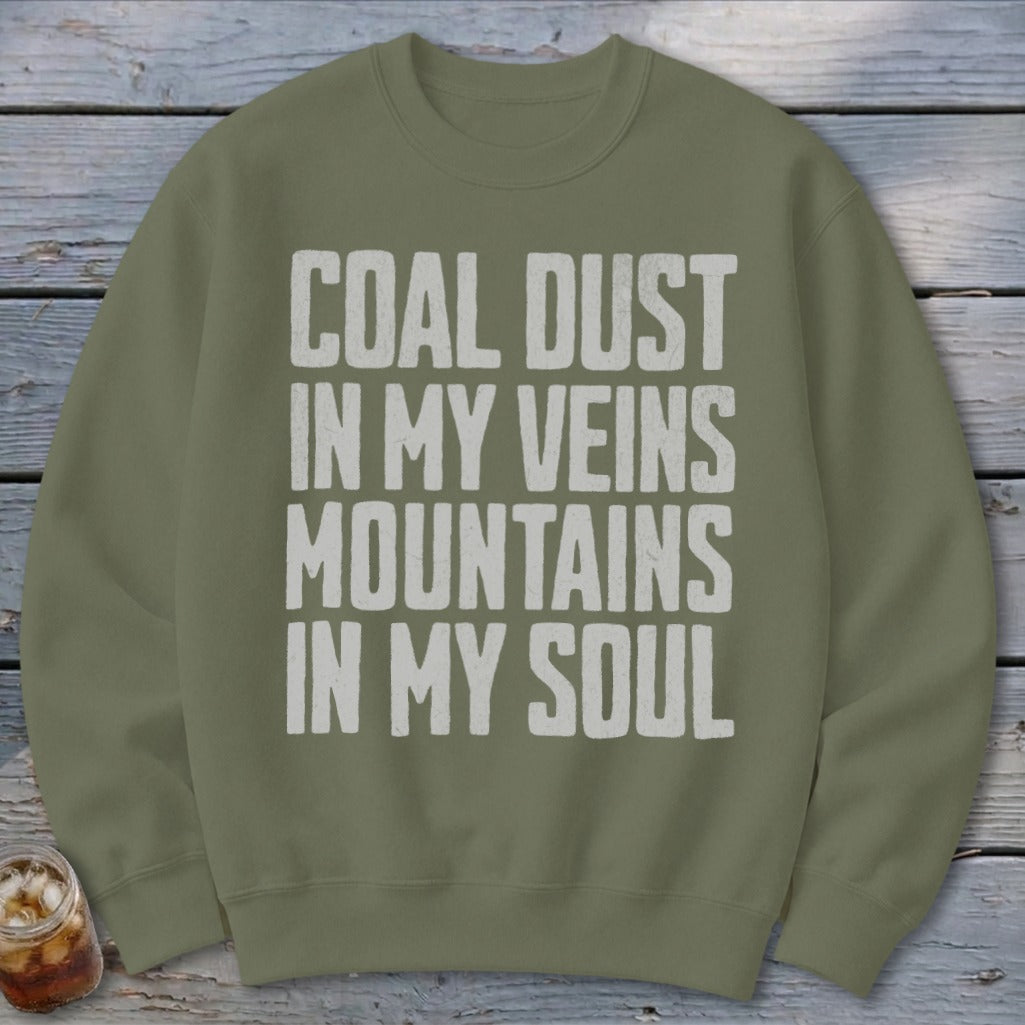 Olive green crewneck sweatshirt featuring distressed white text that reads COAL DUST IN MY VEINS MOUNTAINS IN MY SOUL.