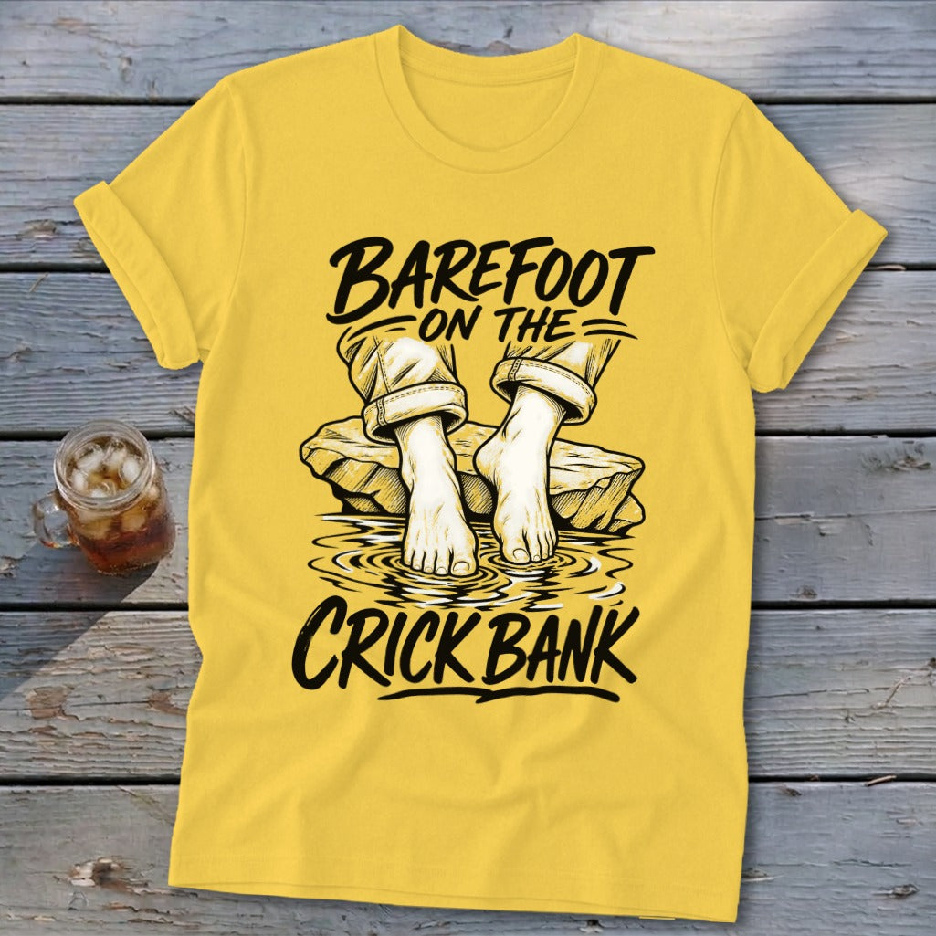 Yellow t-shirt with "Barefoot on the Crick Bank" text and illustration of feet in water.