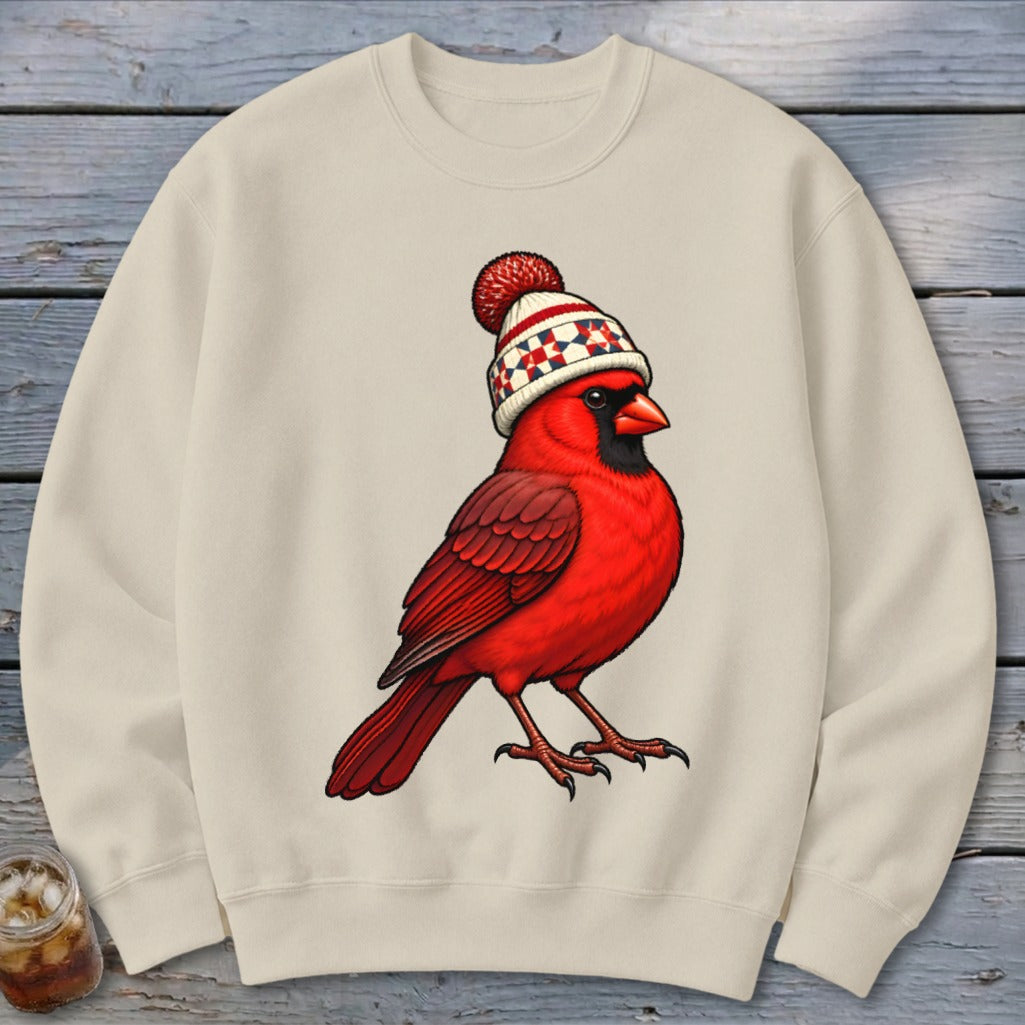 Beige crewneck sweatshirt featuring a graphic of a red cardinal wearing a winter beanie.