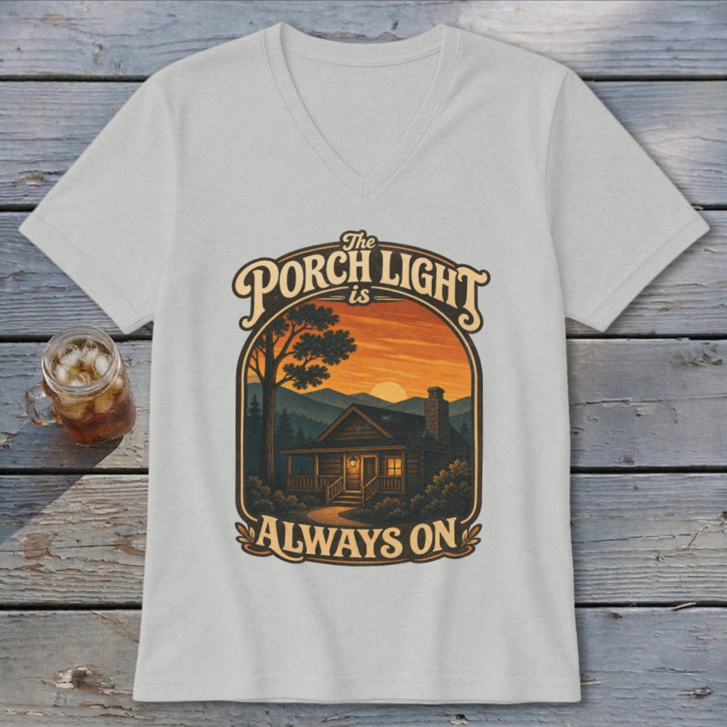 The Porch Light is Always On cabin graphic on a light gray v-neck t-shirt.