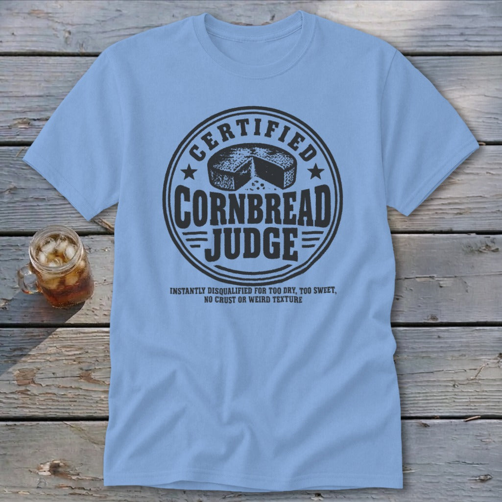 Light blue t-shirt featuring a circular graphic with text reading Certified Cornbread Judge and a cornbread illustration.
