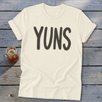 Cream t-shirt with "YUNS" in dark gray text, beside a mason jar drink.