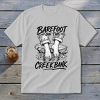 White t-shirt with illustration "Barefoot on the creek bank" and bare feet.