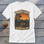 White t-shirt with graphic of a cabin at sunset and text "The Porch Light is Always On".