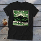 Black t-shirt featuring a green graphic of mountains and text reading Born in the Holler Raised on the Ridge.
