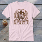 Light pink t-shirt with a brown lantern graphic and "ESTABLISHED IN THE HILLS" text.