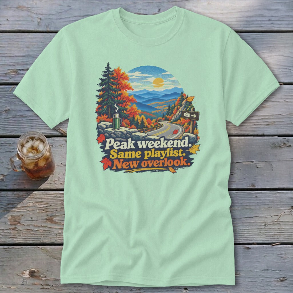 Mint t-shirt with "Peak weekend. Same playlist. New overlook." text and mountain landscape graphic.