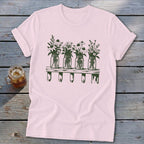 Light pink short-sleeve t-shirt featuring a green graphic of four mason jars filled with wildflowers resting on a wooden shelf.