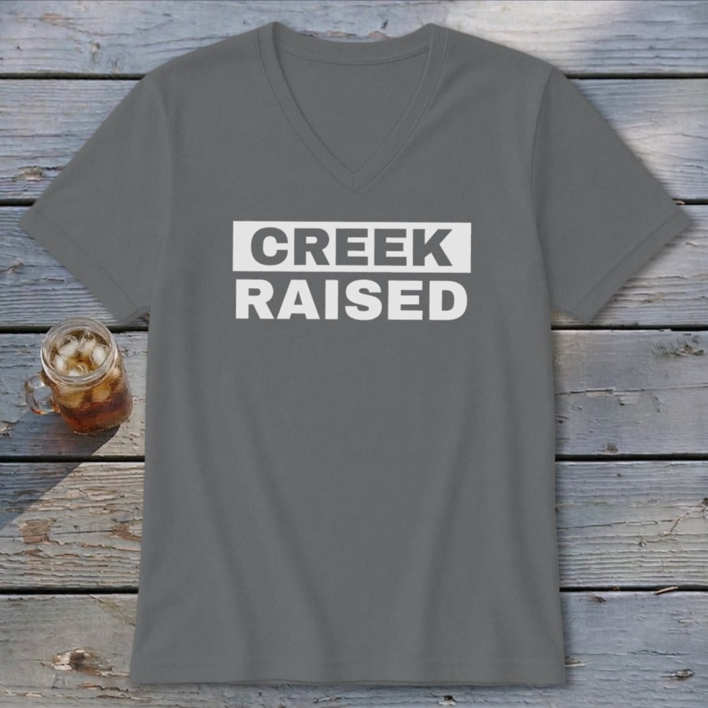 Grey v-neck t-shirt with "CREEK RAISED" in white text on a white rectangle.
