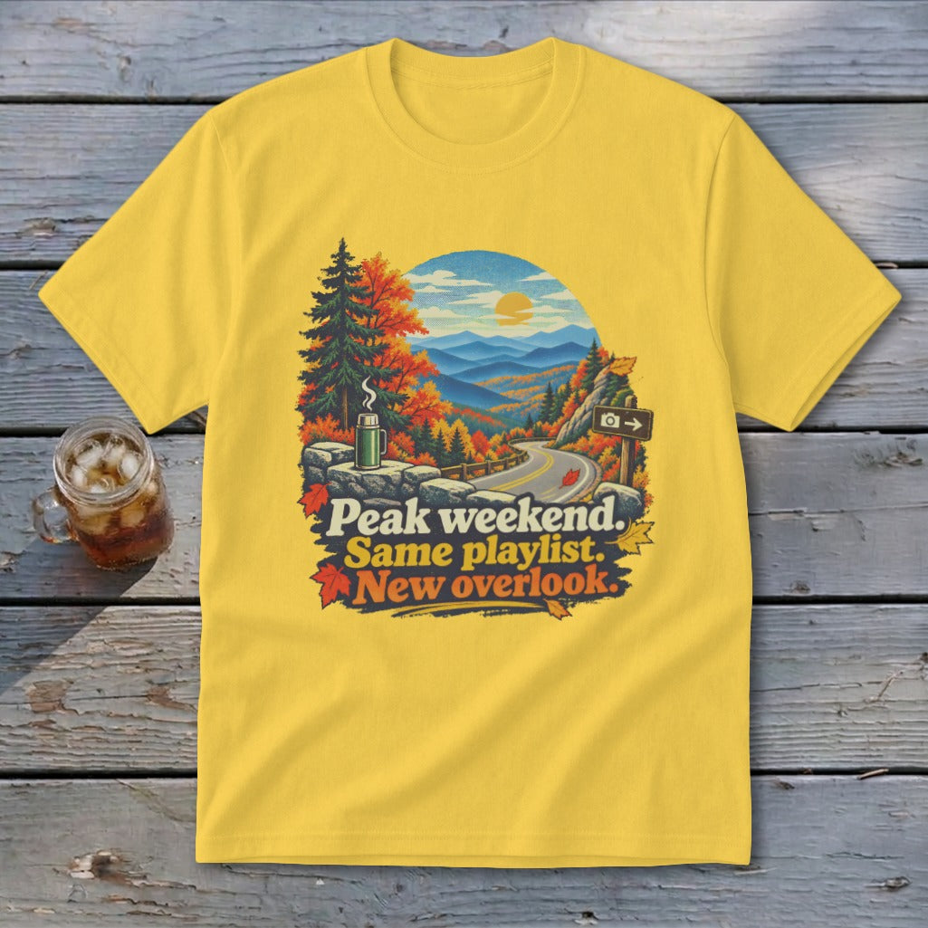 Yellow t-shirt with autumn mountain overlook graphic and text "Peak weekend. Same playlist. New overlook."