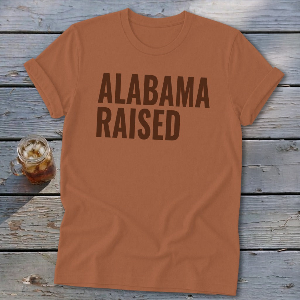 Orange t-shirt with "Alabama Raised" text in brown and a glass of iced tea.