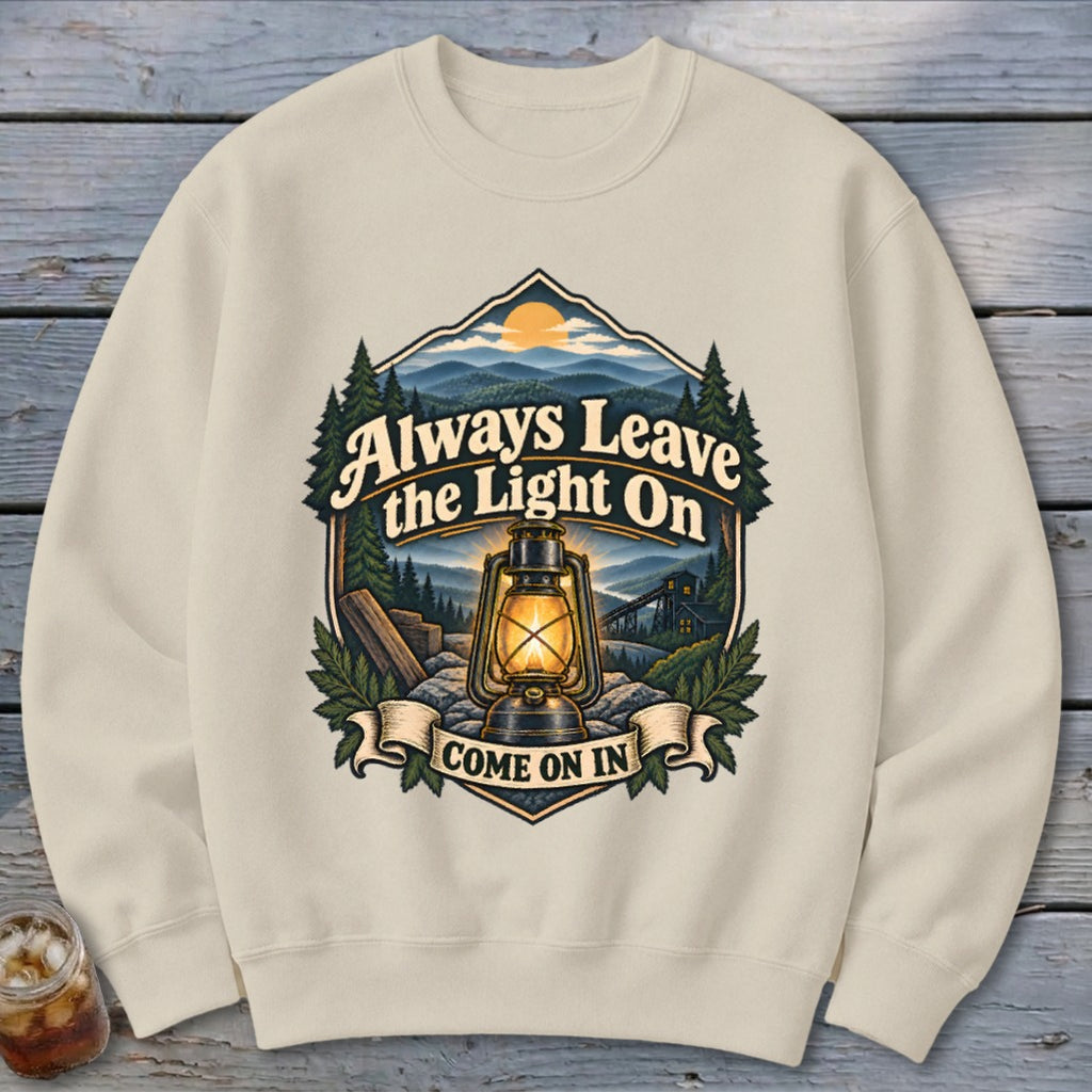 Crewneck sweatshirt with a graphic of a lantern, mountains, and text "Always Leave the Light On Come On In".