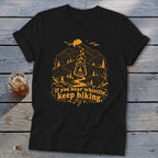 Black t-shirt with orange graphic of lantern, mountains, trees, and text "If you hear whistlin', keep hiking."
