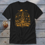 Black t-shirt with a mountain scene and "If you hear whistlin', keep hiking."