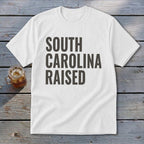 White t-shirt with "SOUTH CAROLINA RAISED" text in dark gray.
