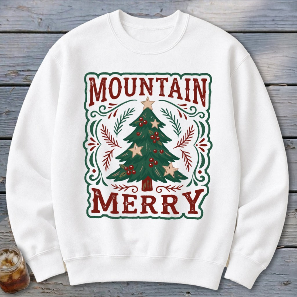 A white crewneck sweatshirt features a green-bordered graphic with a Christmas tree and the text Mountain Merry.