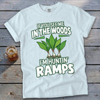 A light blue t-shirt with green text reading IF YOU SEE ME IN THE WOODS I'M HUNTIN' RAMPS and an illustration of three ramp plants.
