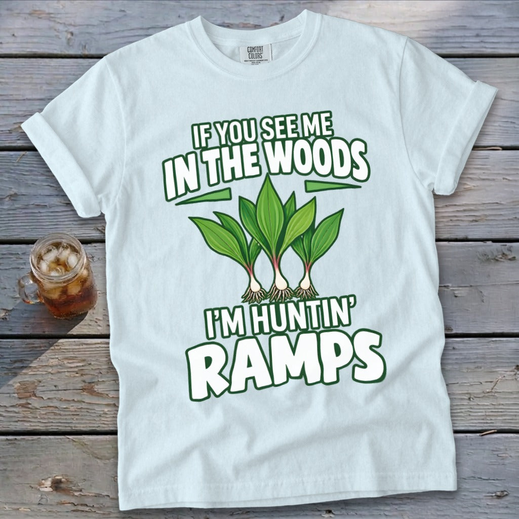 A light blue t-shirt with green text reading IF YOU SEE ME IN THE WOODS I'M HUNTIN' RAMPS and an illustration of three ramp plants.