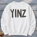 White crewneck sweatshirt with bold dark gray "YINZ" text across the chest.