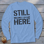 Light blue long sleeve shirt with black text that reads "STILL HERE" and a mountain silhouette.